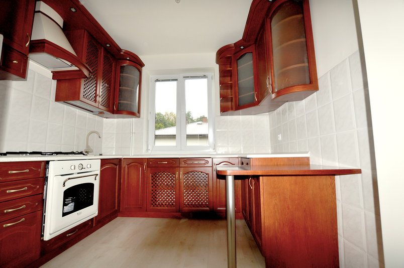 Klasyczna kuchnia wiśniowa na wymiar Jasło – drewniane fronty z przeszkleniami, wiszące szafki, blat laminowany, zlew podwieszany, piekarnik